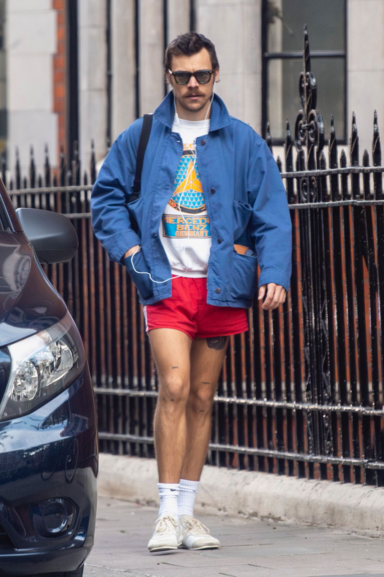 Image may contain Harry Styles Clothing Shorts Adult Person Car Transportation Vehicle Standing Footwear and Shoe